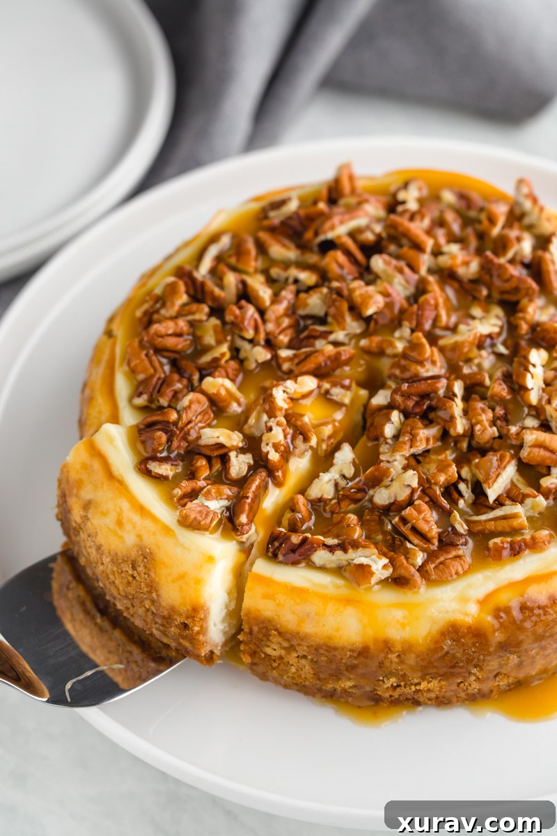 A whole instant pot cheesecake topped with caramel and pecans, with a slice cut and partially pulled out. 