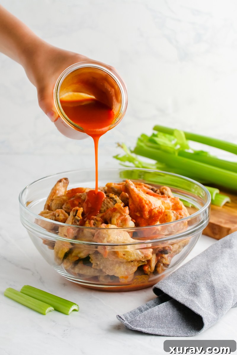 Pouring buffalo sauce over hot wings to make buffalo wings