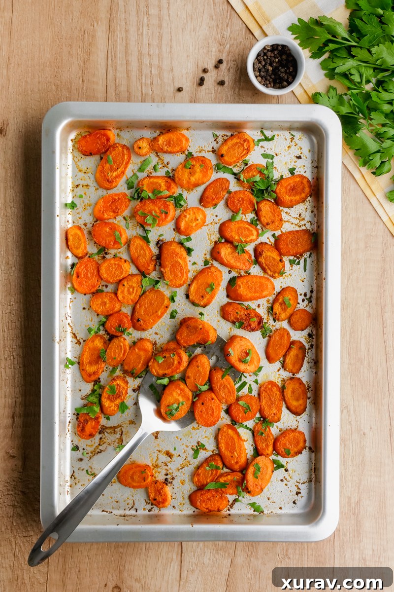 Roasted carrots being scooped from a pan onto a serving plate