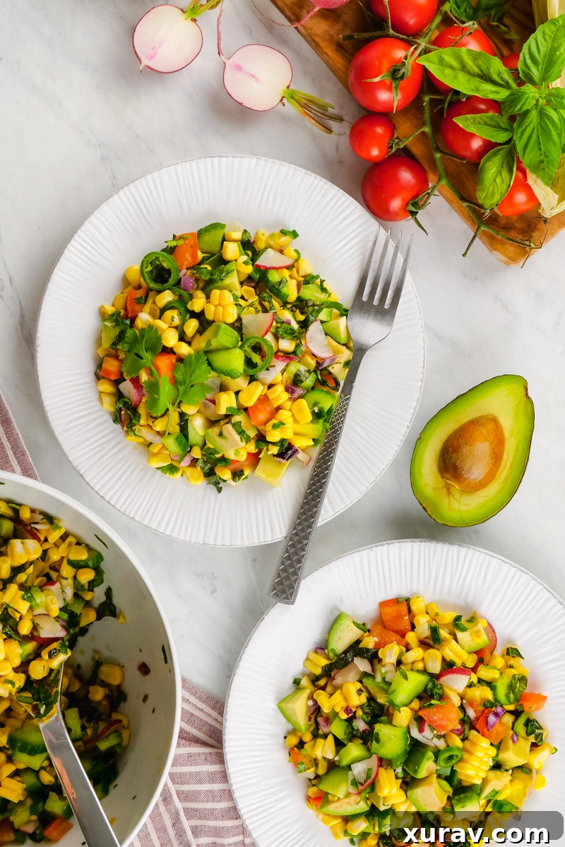 A bowl of fresh corn salad next to corn on the cob