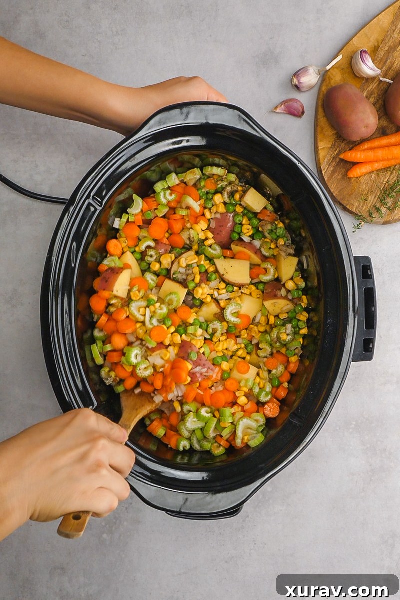 A golden brown biscuit being placed on top of slow cooker chicken pot pie.