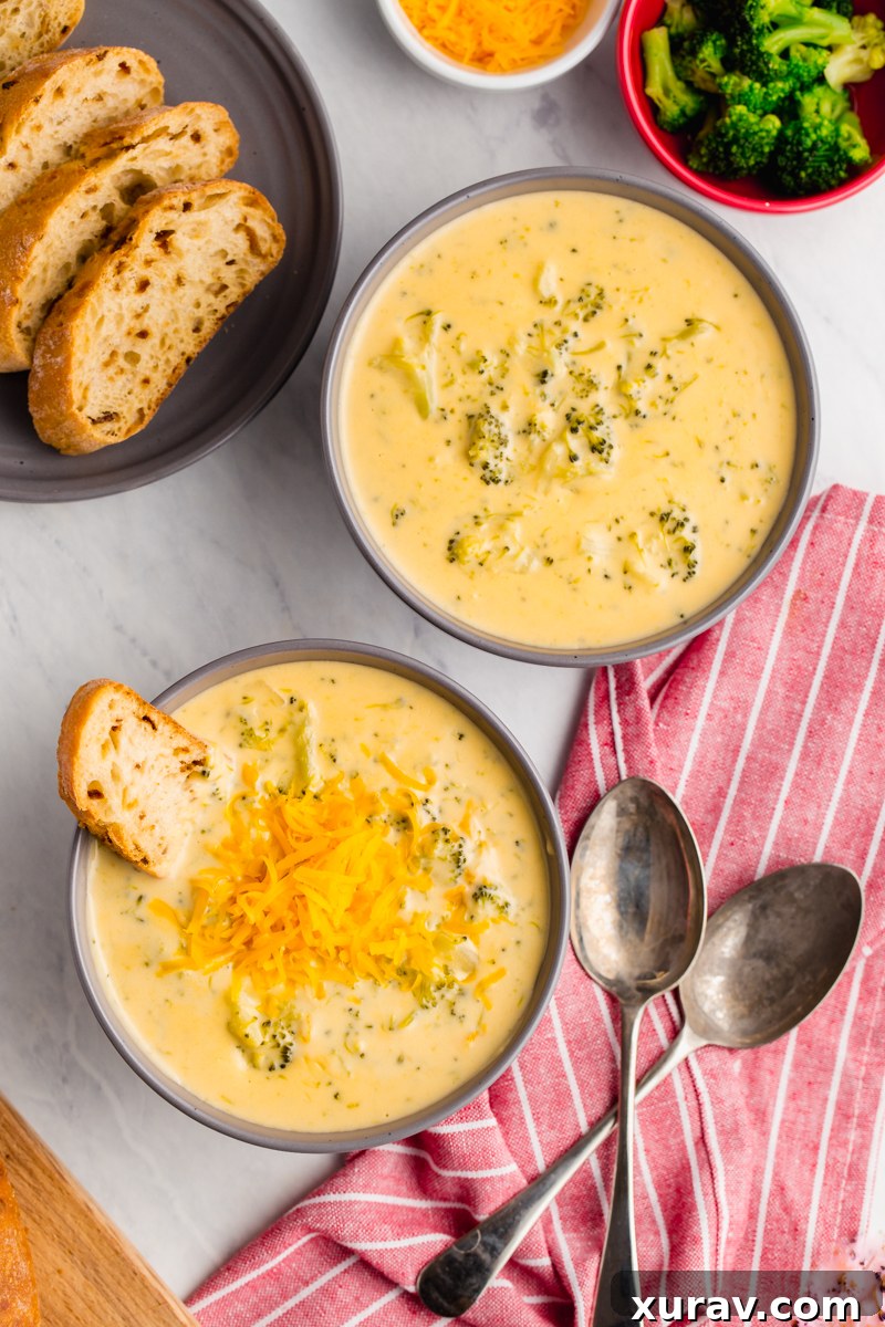 A large pot of creamy broccoli cheese soup simmering on the stovetop, with steam rising, indicating it's hot and ready.