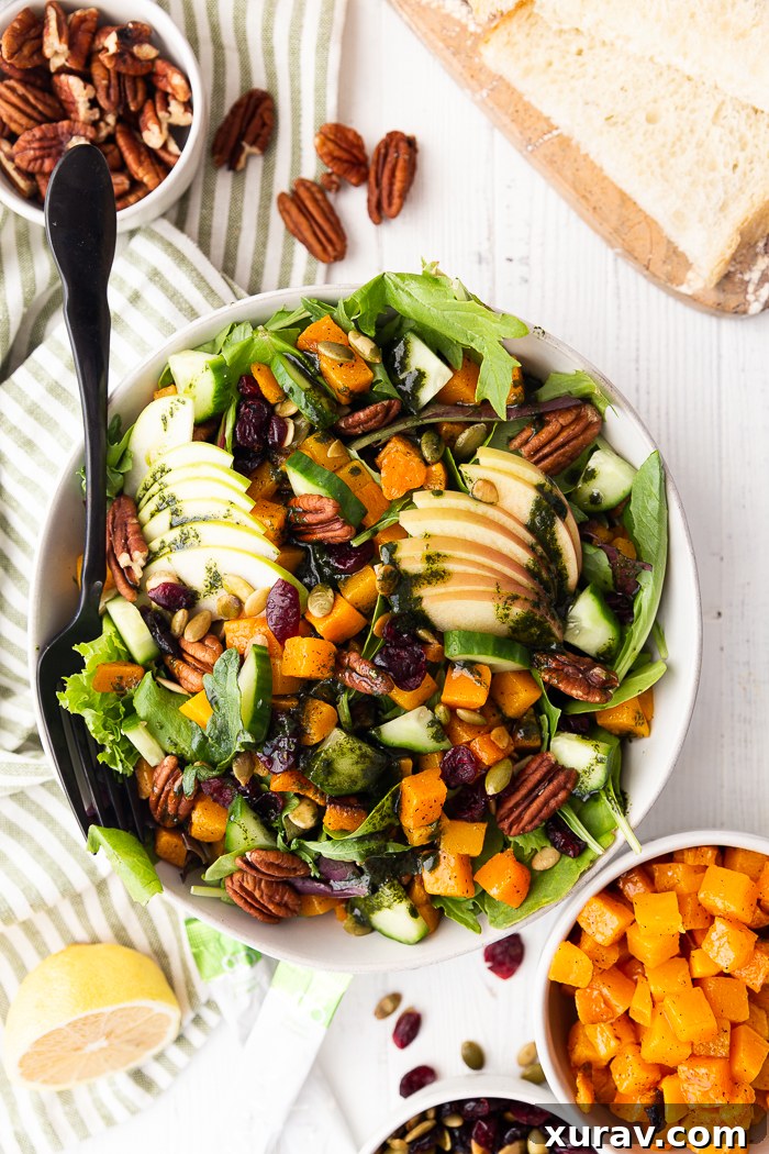 Vibrant Fall Harvest Salad with roasted butternut squash, apples, pecans, cranberries, and a green dressing.