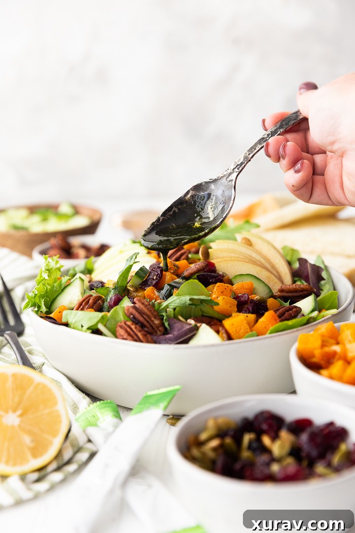 A close-up of the Fall Harvest Salad being dressed with the homemade green vinaigrette, showcasing its vibrant appeal.