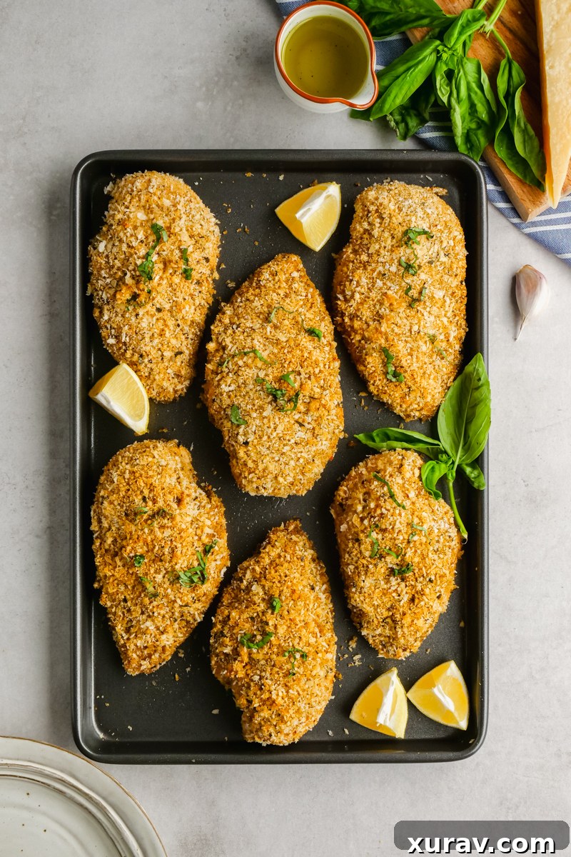Four golden baked breaded chicken breasts resting on a cutting board, ready to be served.