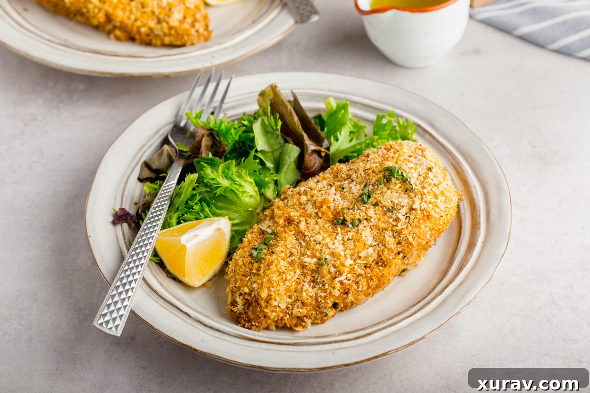 A close-up shot of a single piece of baked breaded chicken, sliced to reveal its juicy interior.