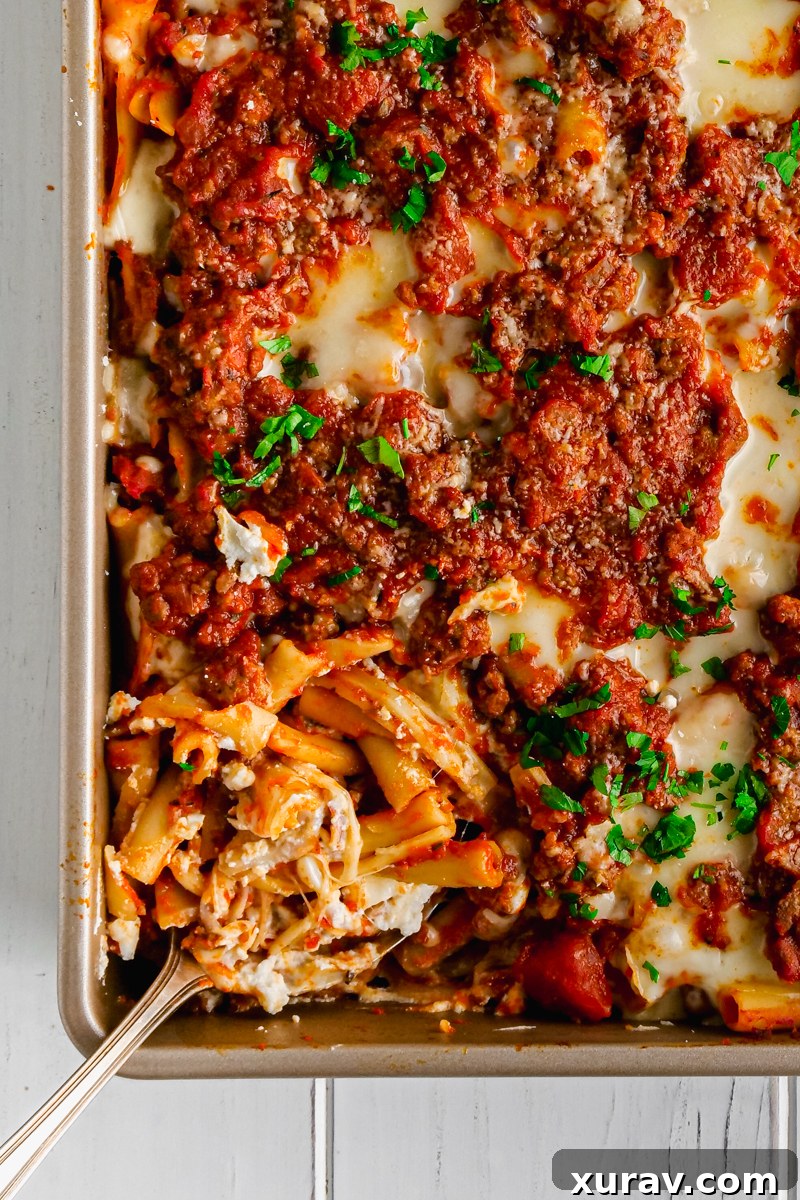 Baked Ziti casserole with ground beef, sausage, and a blend of cheeses, served in a white baking dish.