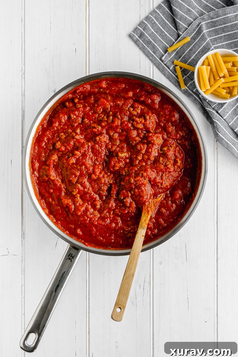 A close-up shot of the rich, homemade tomato meat sauce simmering in a skillet, ready for the baked ziti.