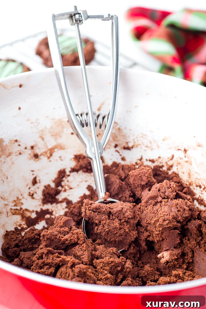 Close-up of baked chocolate mint thumbprint cookies on a cooling rack, showing the vibrant green mint filling