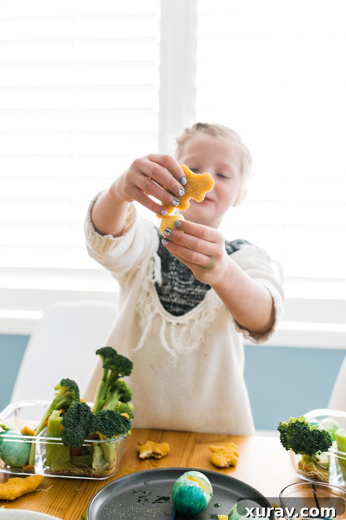 A child's hand reaching for a Yummy Dino Buddy nugget in a bento box.