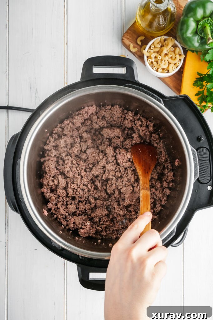 Close-up of ground beef browning in the Instant Pot on the sauté function, ready for the next step of American Goulash preparation.