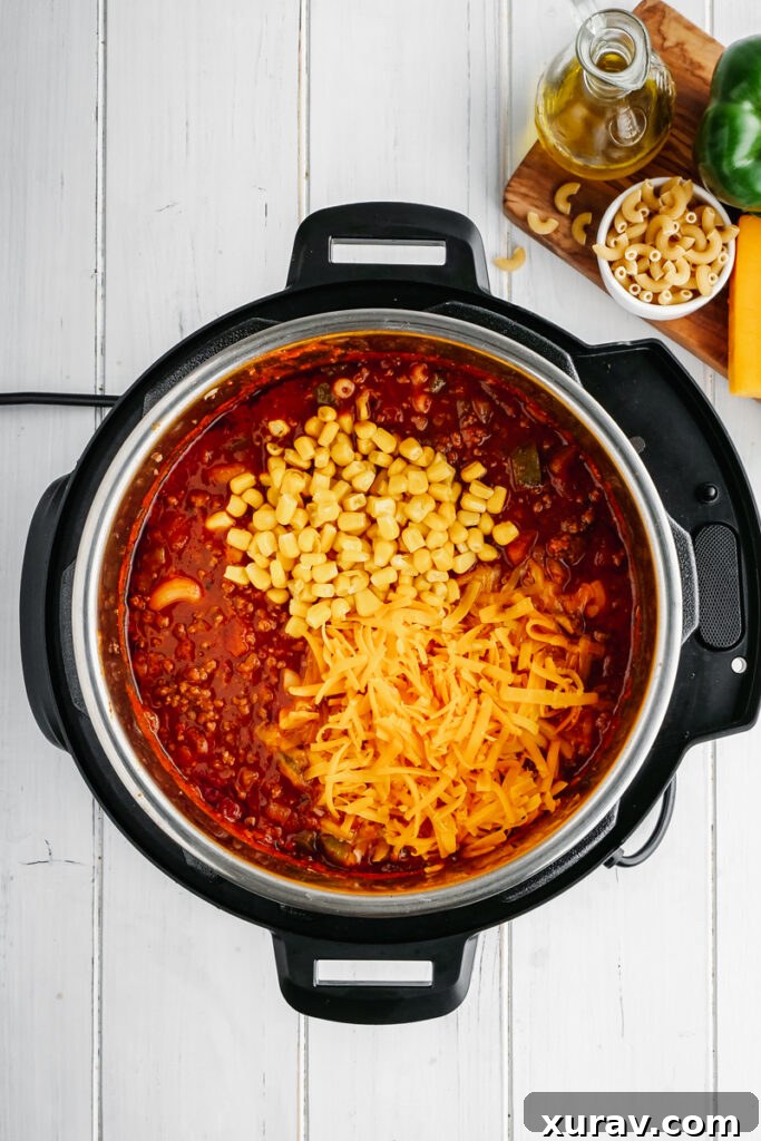 The finished Instant Pot American Goulash, with melted cheddar cheese and sweet corn stirred into the rich tomato and macaroni mixture.