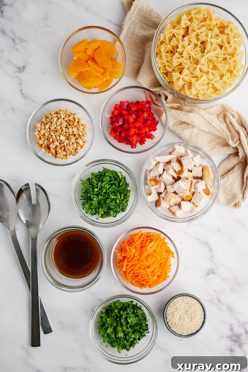 Small prep bowls with all the ingredients you need for Asian Pasta Salad, with utensils on the left side.