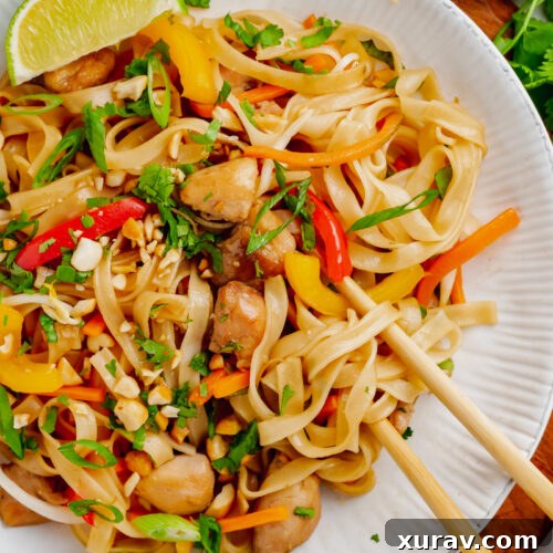 A white plate with Instant Pot Pad Thai, chopsticks, a lime, and toppings