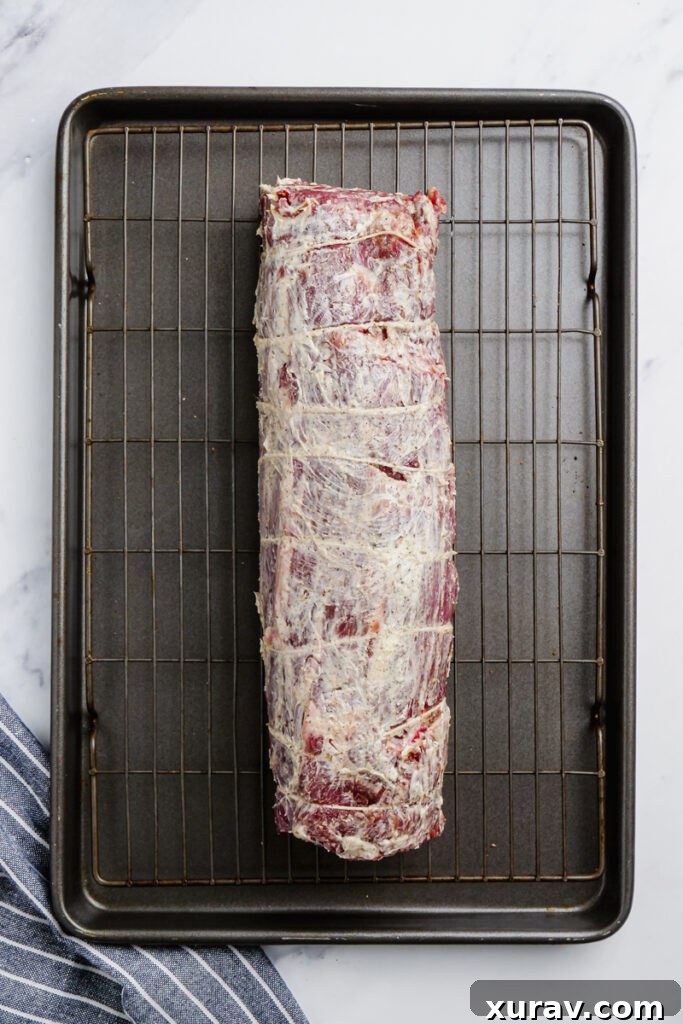 A seasoned butter rub being applied to a roast beef tenderloin