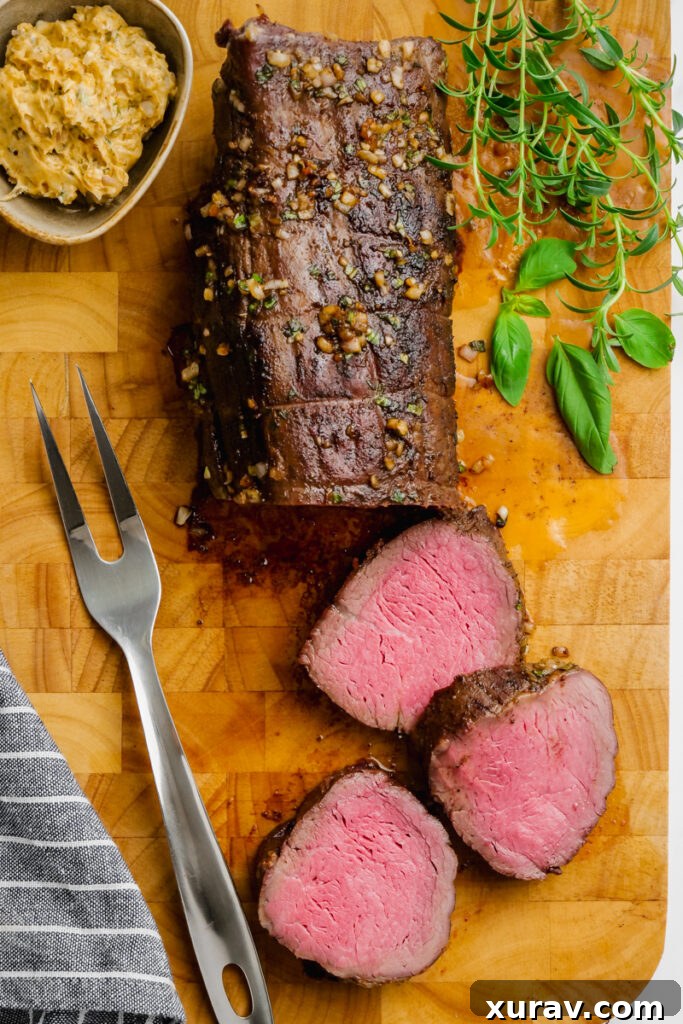 A half carved roast beef tenderloin on a cutting board, showcasing its juicy interior