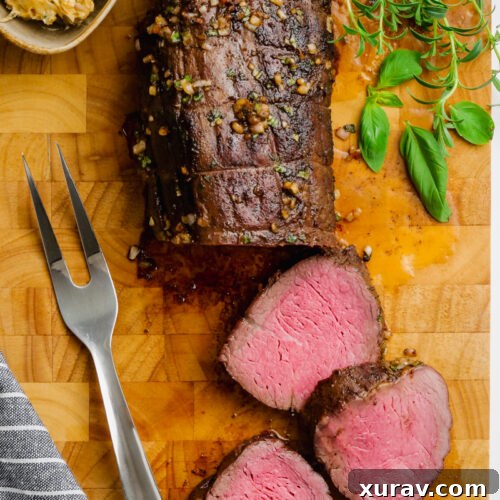 A half carved roast beef tenderloin on a cutting board