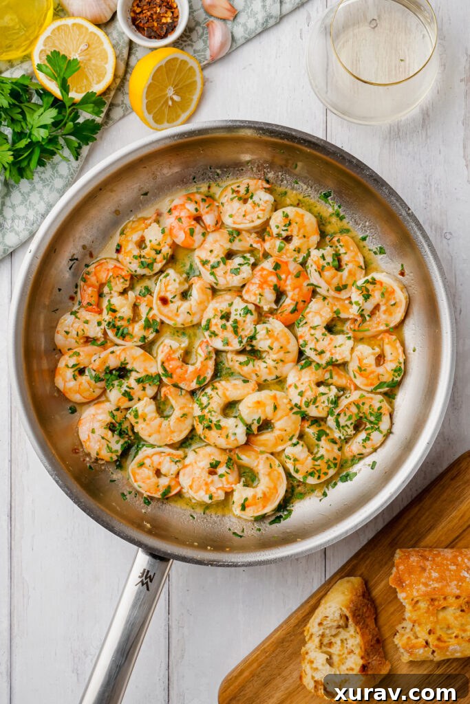 Shrimp scampi simmering in a pan, coated in a luscious garlic butter sauce.