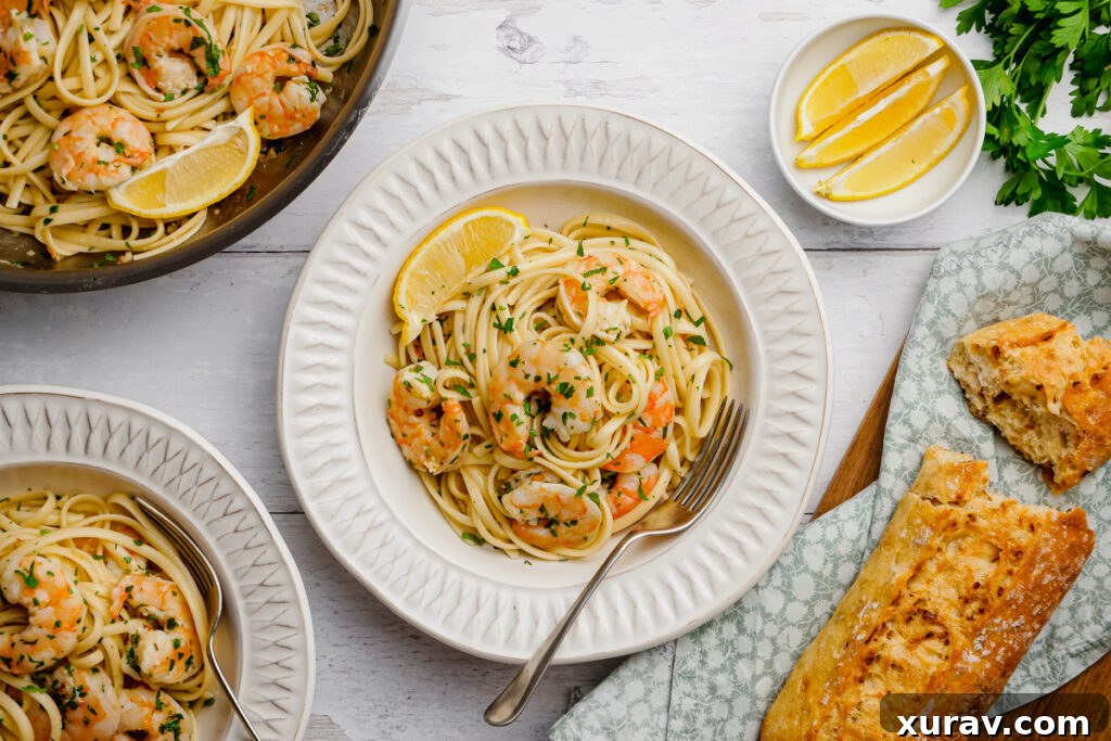 A beautifully plated Shrimp Scampi dish, garnished with fresh lemon wedges and crusty bread on the side.
