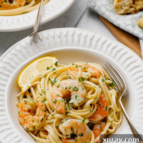 Shrimp Scampi on a white plate with a fork, ready to be eaten.