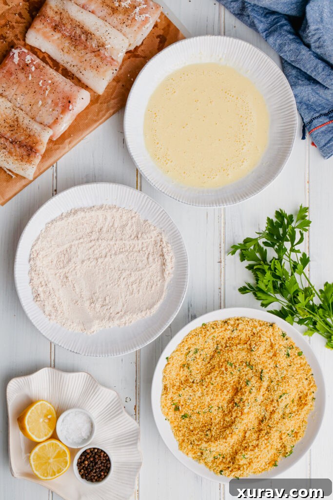 The dredging station for oven fried fish, showing three bowls for flour, egg, and breadcrumbs