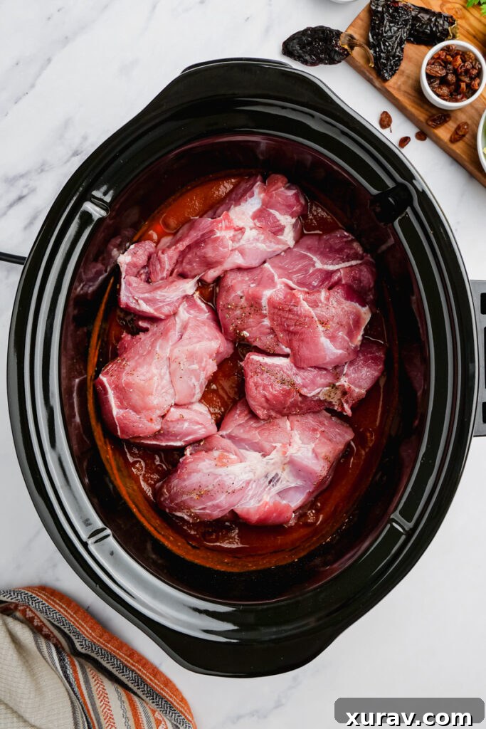 Ingredients for shredded pork mole tacos being combined in a slow cooker.