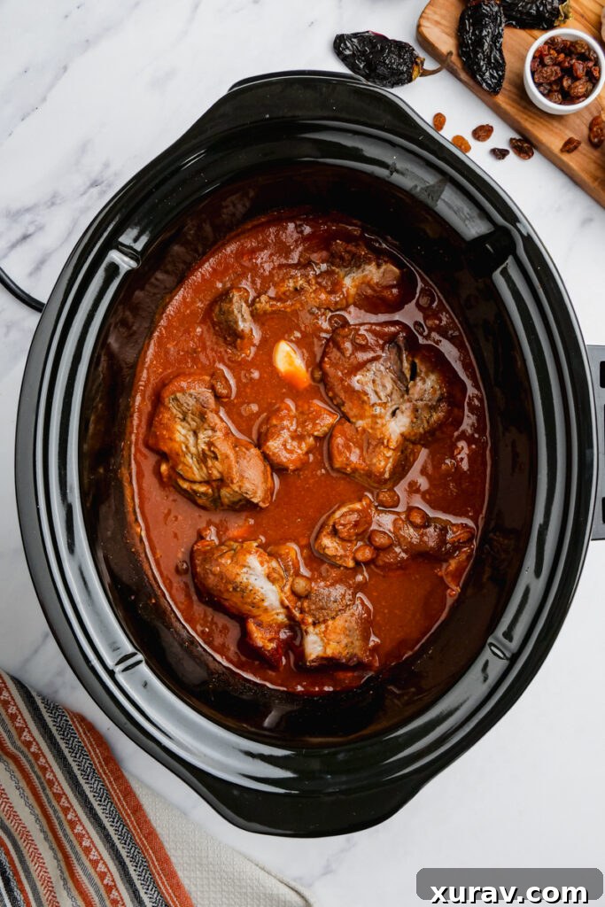 Cooked pork mole for pork tacos simmering in a slow cooker.