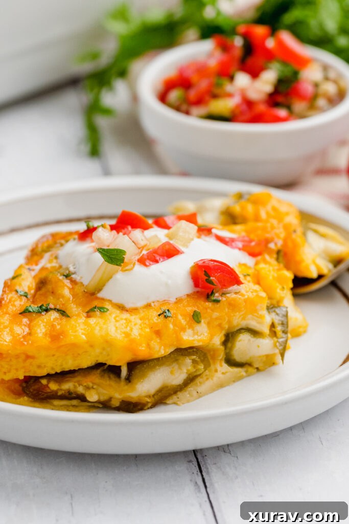A white plate with baked chiles rellenos, topped with a light egg batter and melted cheese