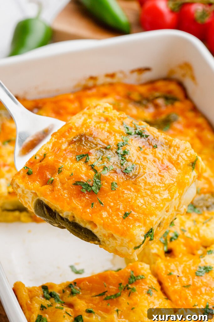 A piece of baked chiles rellenos on a spoon, showing the melted cheese and fluffy egg topping