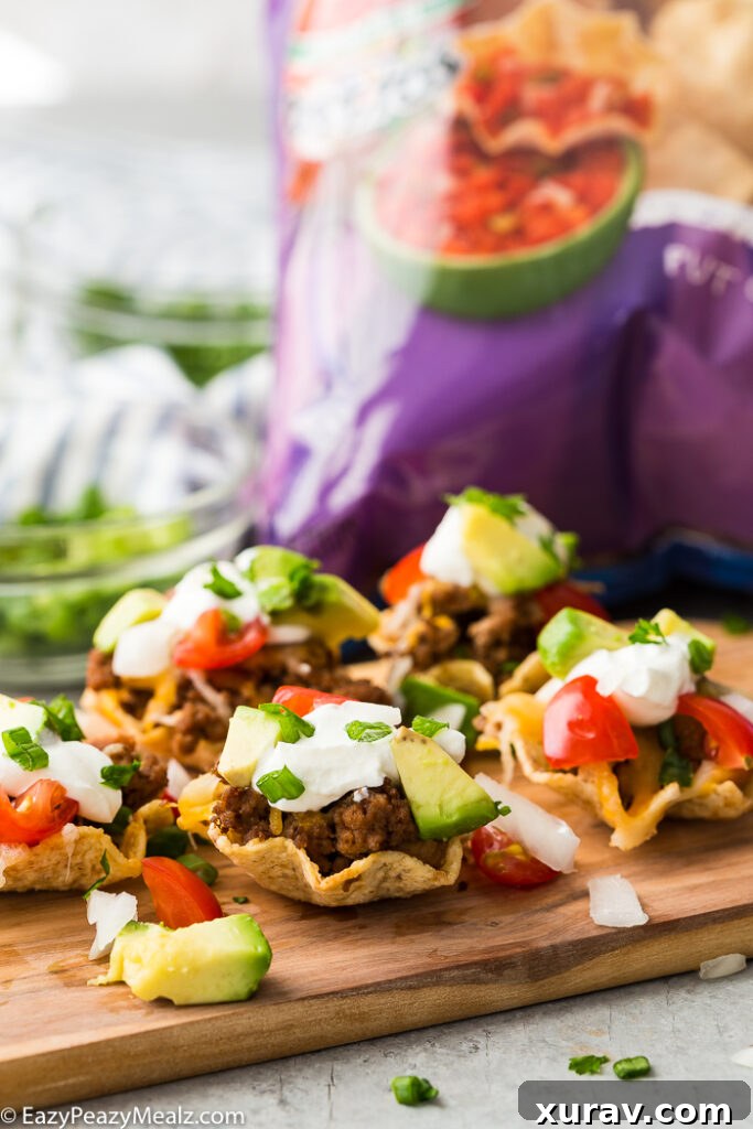 A cutting board with taco bites in Tostitos Scoops! a bag of chips in the background. 