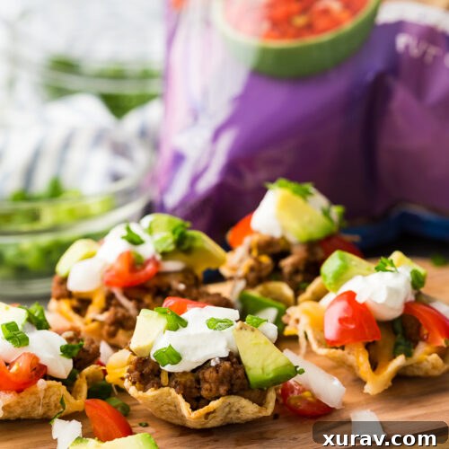 A cutting board with taco bites in Tostitos Scoops! a bag of chips in the background.