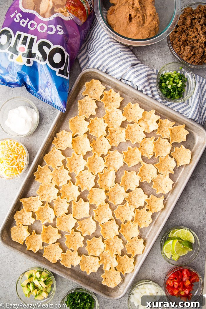 A baking tray covered in Tostitos Scoops with the fixings for taco bites around it.
