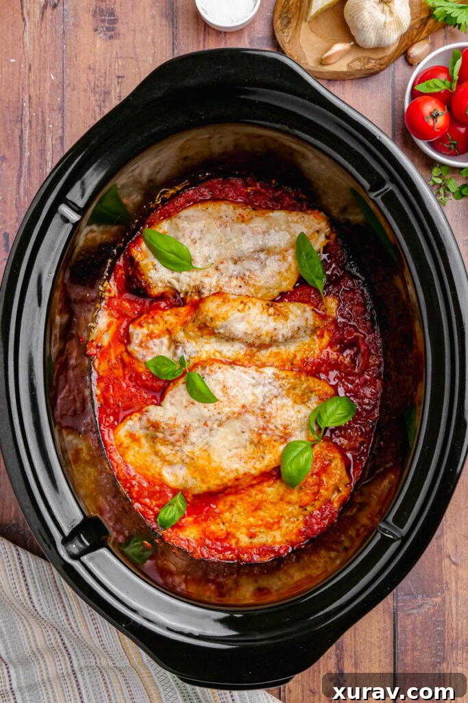 Cooked Slow Cooker Chicken Pomodoro in a black slow cooker, garnished with fresh basil, ready to be served.