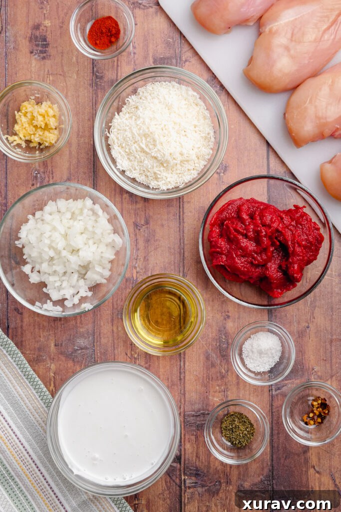 A selection of fresh ingredients laid out, including chicken breasts, onions, garlic, tomato paste, and herbs, ready to make Slow Cooker Chicken Pomodoro.