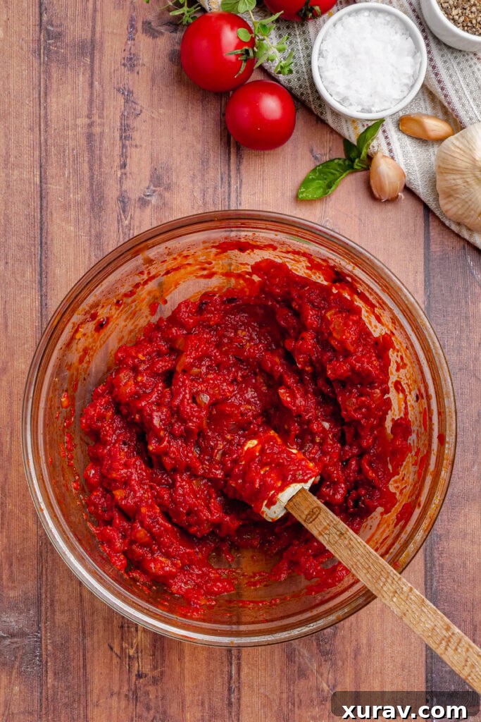 Delicious Chicken Pomodoro sauce, creamy and ready to be combined with chicken, displayed in a glass mixing bowl with a spatula.