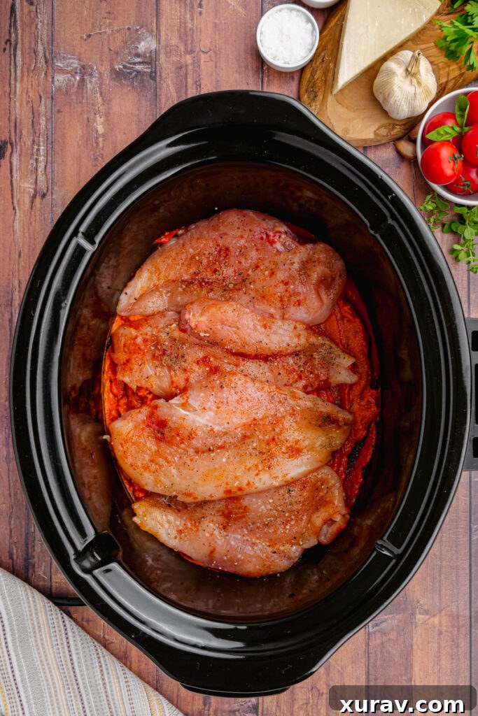 Slow Cooker Chicken Pomodoro simmering in a black Crock-Pot, showing the chicken immersed in the rich sauce.