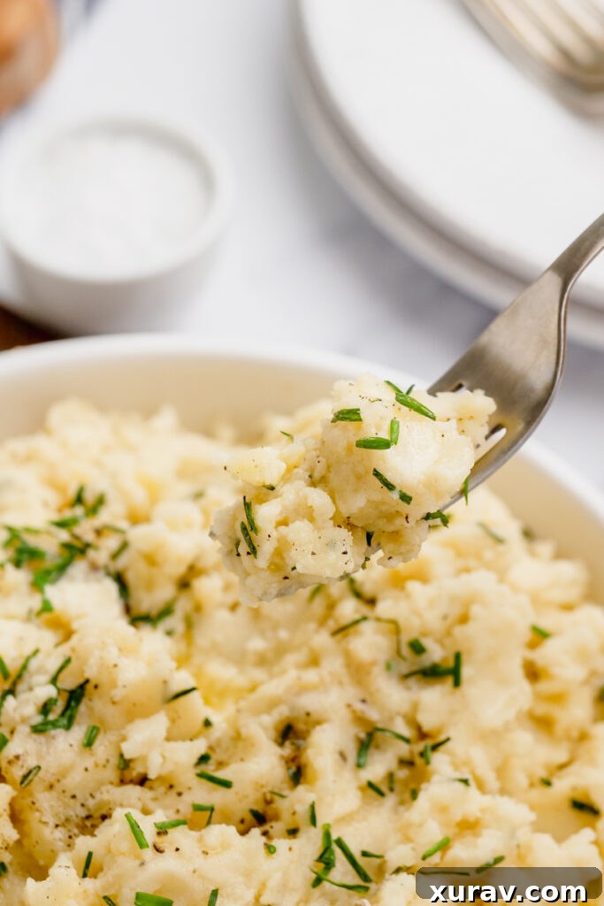 A white bowl filled with creamy slow cooker mashed potatoes, with a fork resting in the side, ready to be enjoyed.