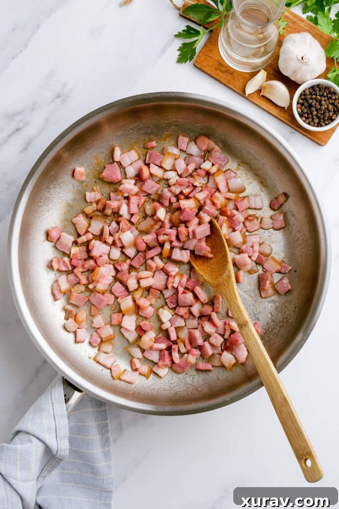 The cooking process for carbonara, showing bacon sizzling in a large skillet, with garlic and pepper ready to be added for a fragrant base.