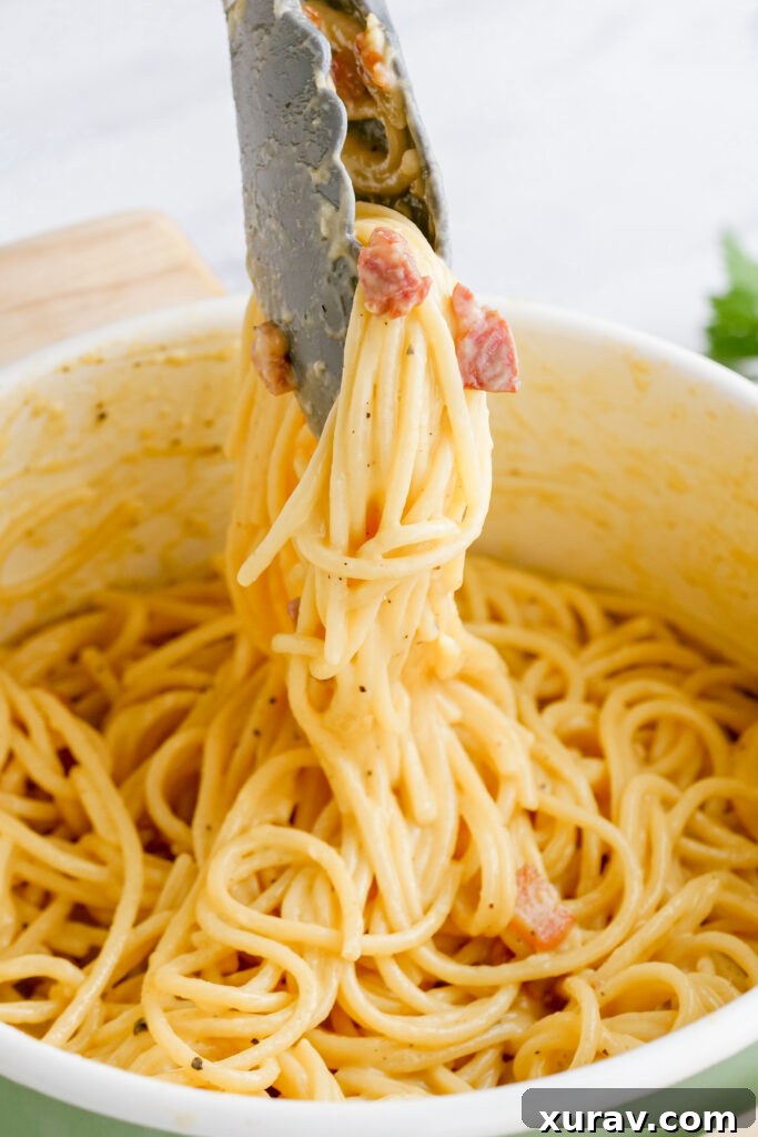 Spaghetti carbonara mixed perfectly in a large skillet, showcasing the creamy sauce and crispy bacon, ready to be plated.