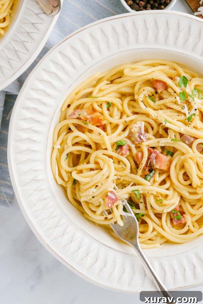 A vibrant, creamy spaghetti carbonara in a deep dish, ready to be served, highlighting its irresistible texture and color.