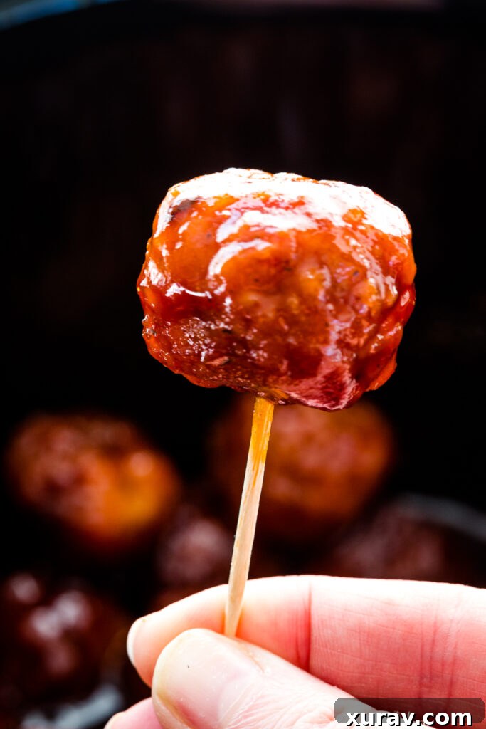 Sticky Sweet Slow Cooker Meatballs 5 Close-up of a single crockpot grape jelly meatball, perfectly glazed and ready to eat.