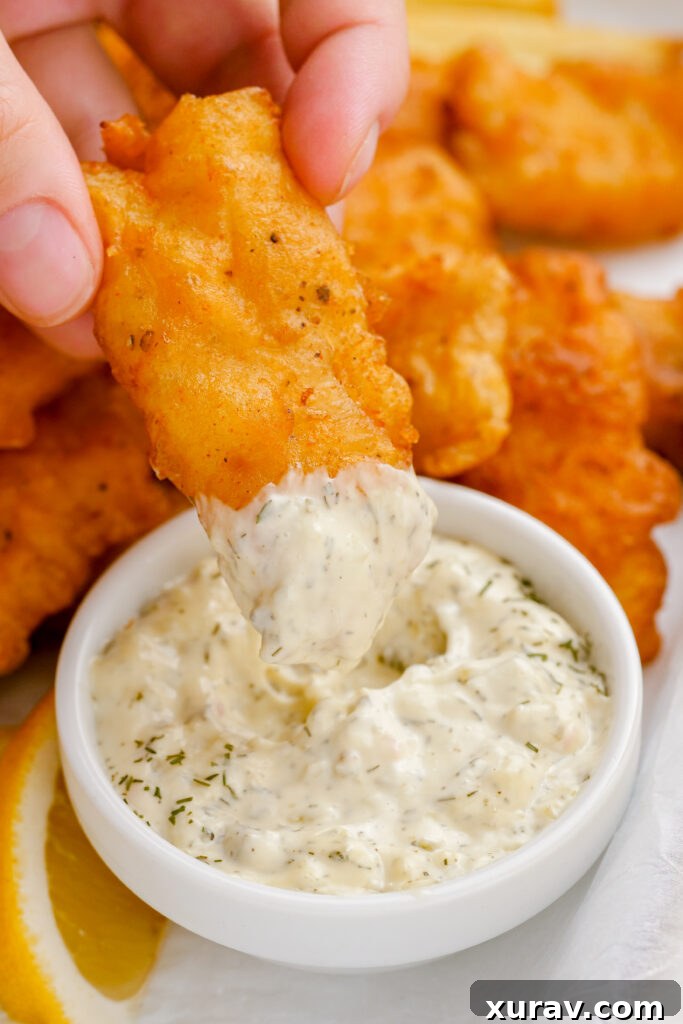 Fried fish being dipped into tartar sauce