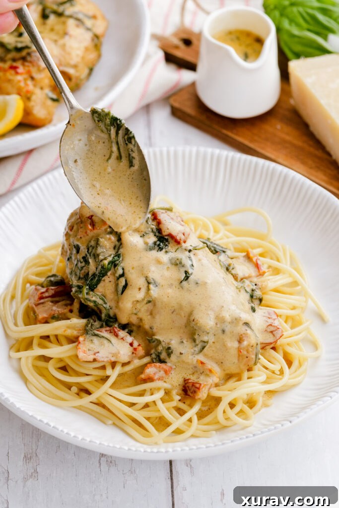 A piece of instant pot tuscan chicken with a spoon placing sauce over the top.