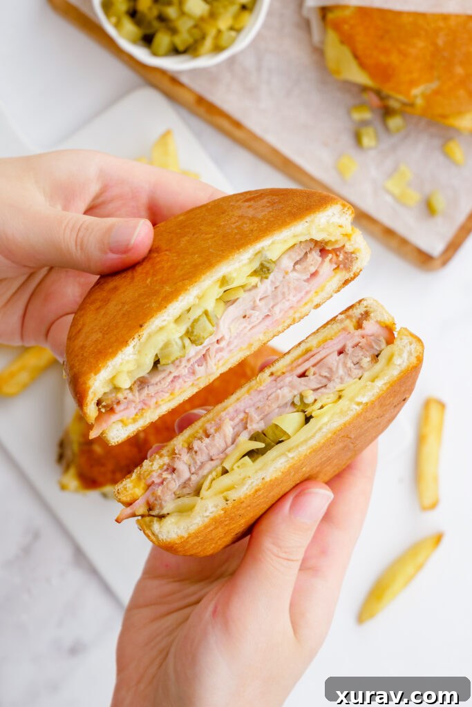 A perfectly pressed Cuban sandwich, golden brown and sliced in half, revealing the delicious layers of meat, cheese, and pickles.