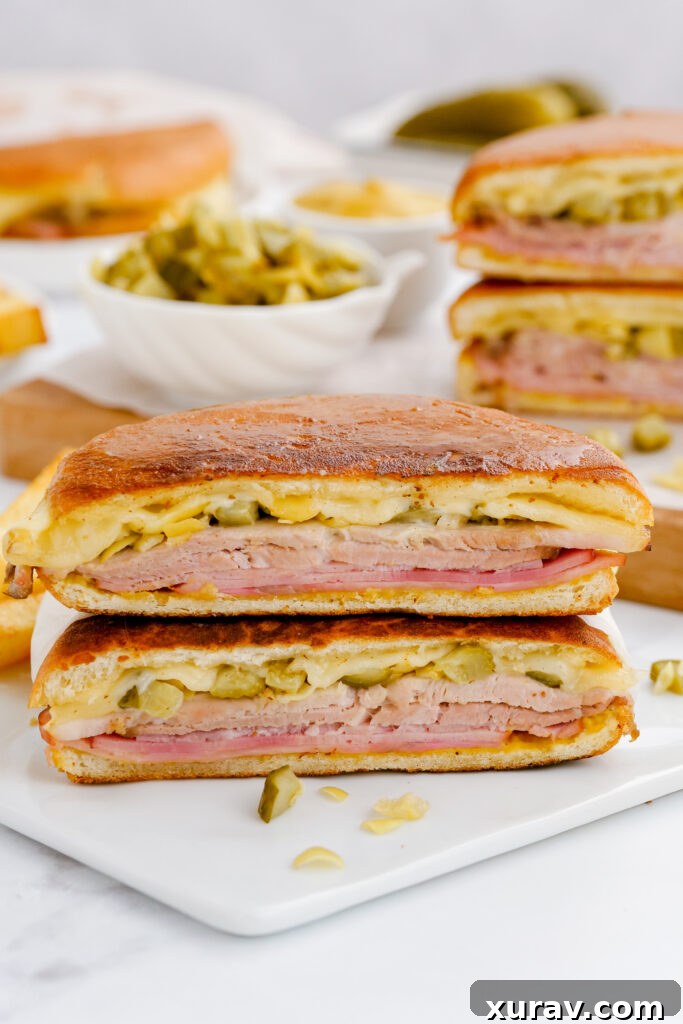 Various ingredients for a Cuban sandwich laid out on a cutting board: sliced ham, roast pork, Swiss cheese, pickles, and banana peppers.