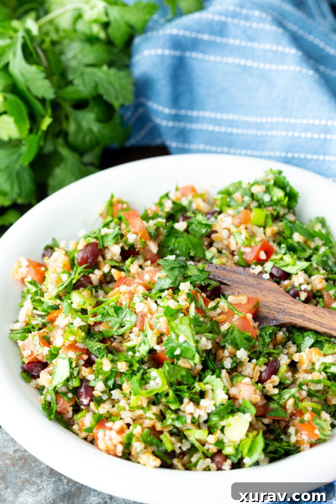 A plate of tabbouleh, a fresh herb salad with vibrant pomegranate arils, ripe tomatoes, and chewy bulgur. This image showcases the salad's fresh ingredients and appealing presentation.