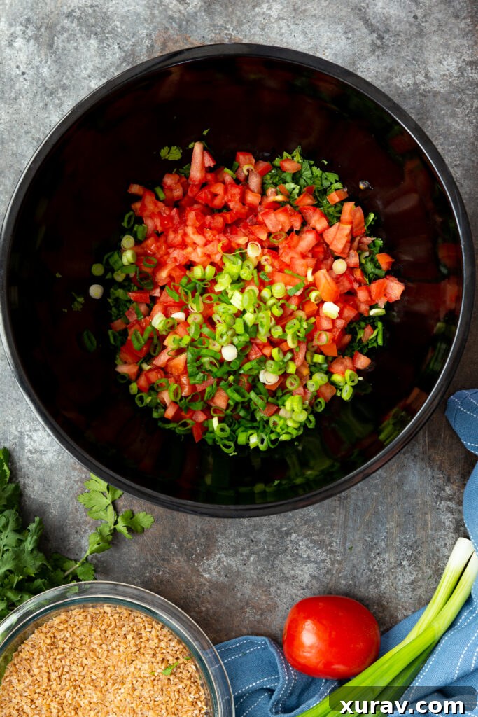Various fresh ingredients for an Israeli tabbouleh salad being gently combined in a sleek black mixing bowl, showcasing the careful assembly process.