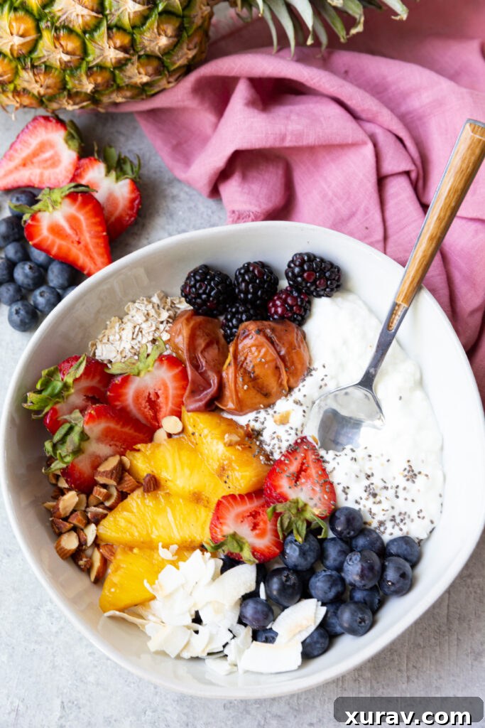 A cottage cheese breakfast bowl with grilled fruit and berries, oats, coconut, nuts, and chia seeds. 