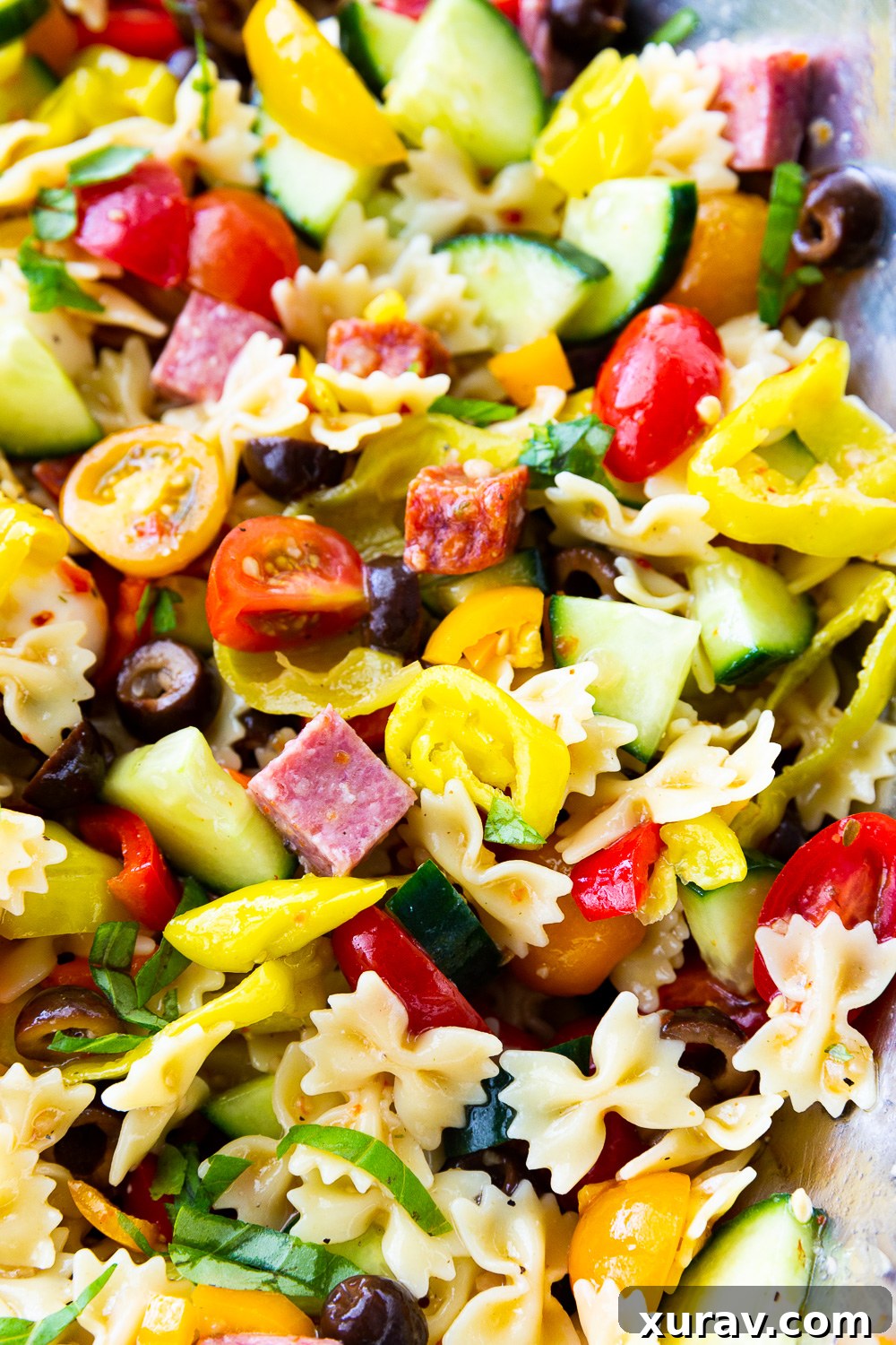 A close-up shot of the finished easy pasta salad, glistening with dressing and packed with colorful ingredients, ready to be enjoyed.
