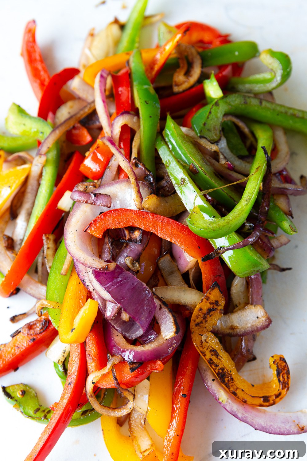 Vegetables cooked on a griddle for chicken fajitas, showcasing a beautiful char and vibrant colors.